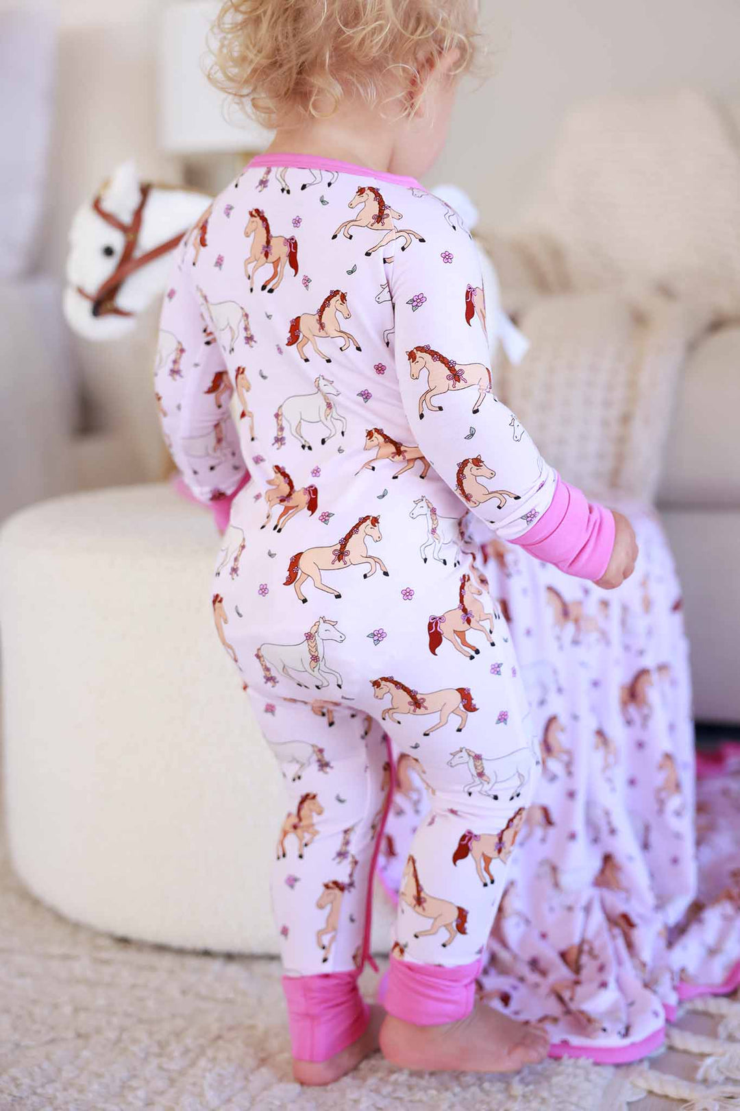 standing baby girl wearing the pony club pink convertible zip romper 