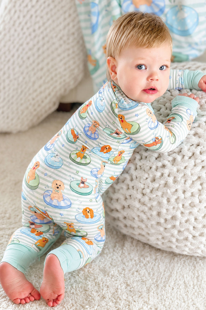 baby boy kneeling against ottoman in blue poolside pups pajama romper