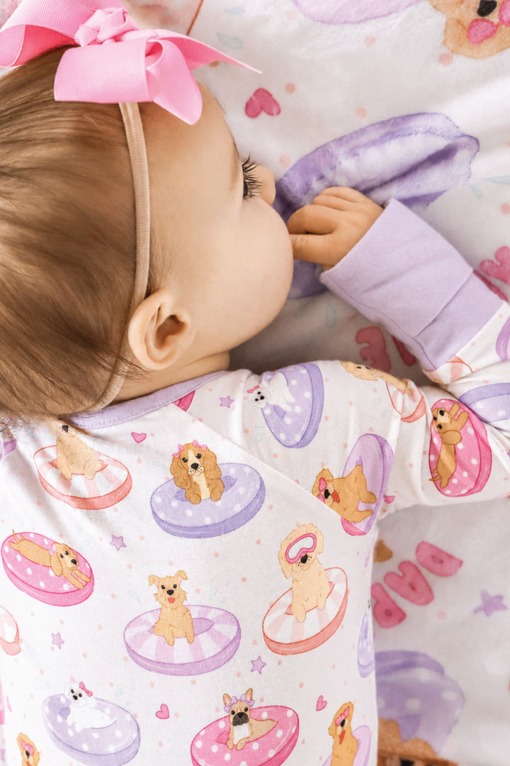 baby girl laying on stomach in poolside pups convertible zip romper with matching personalized blanket