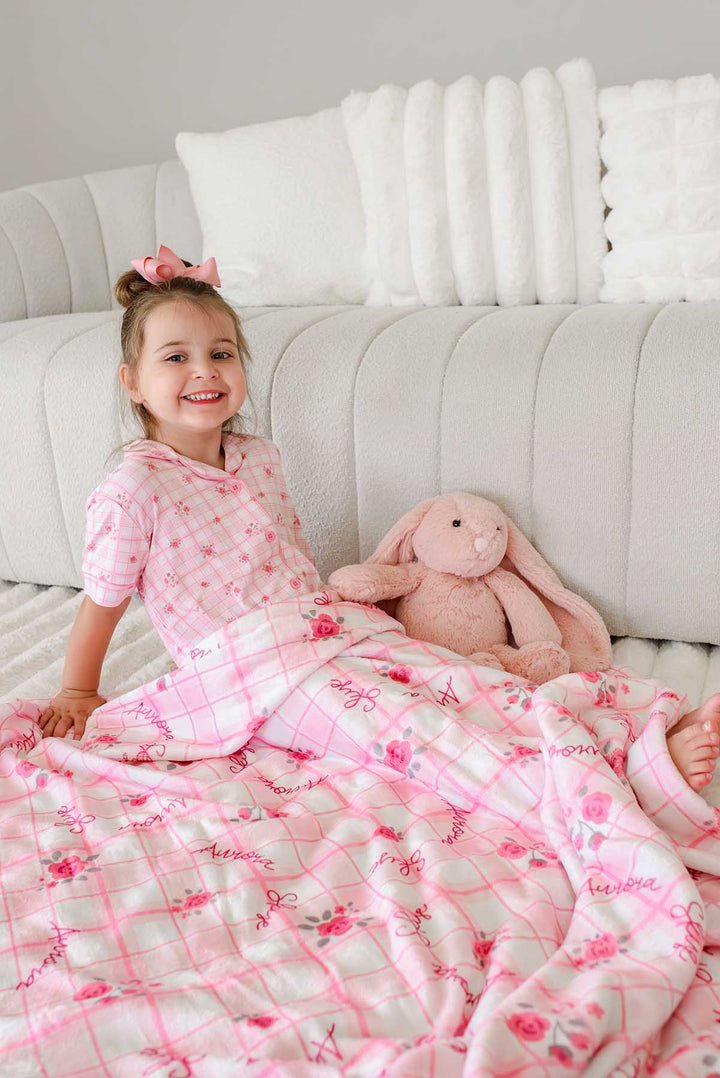 Smiling girl on couch with bunny toy under personalized blanket