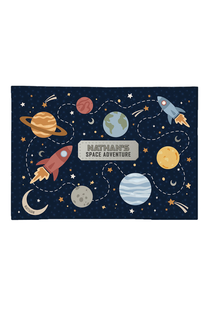 Caden Lane personalized 5x7 space play rug with planets, rockets and dotted paths on navy, reading "Nathan's Space Adventure"