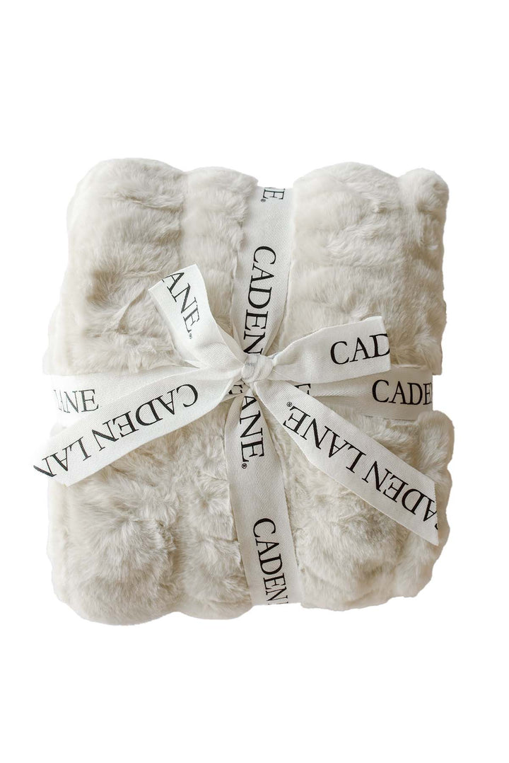 Folded double-ruched faux fur baby blanket in sand tan, tied with a Caden Lane ribbon