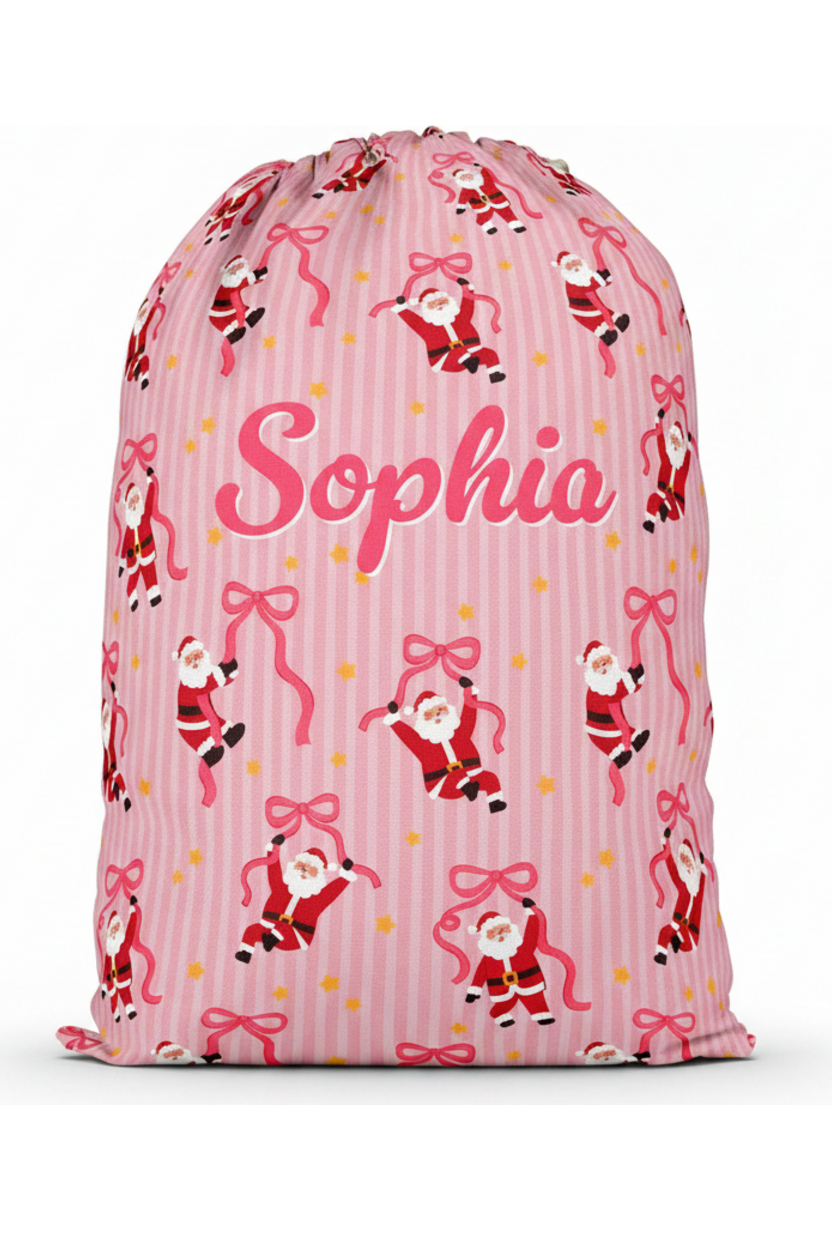 Personalized Caden Lane Jolly Ribbons Christmas Santa Sack featuring a custom name, festive pink stripes, whimsical Santa print, and ribbon design for Christmas gifts and holiday traditions.