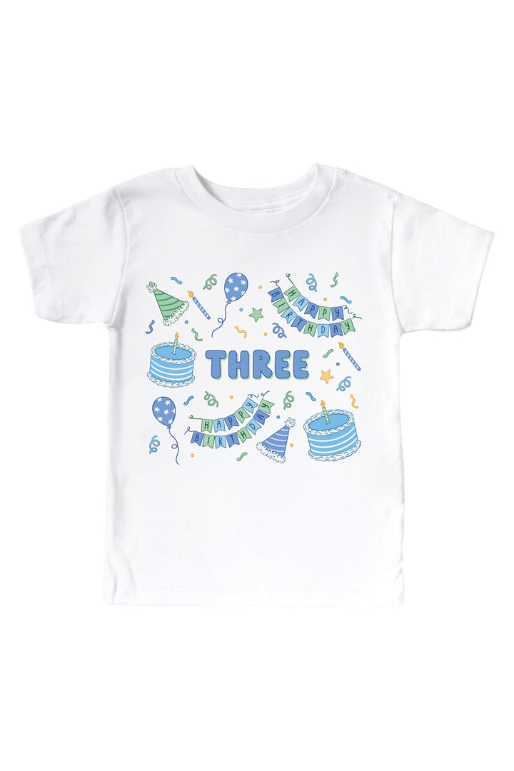 Caden Lane Birthday Bash white kids' t-shirt with "THREE" printed in blue bubble letters, surrounded by cake and party hat print in blue and green.