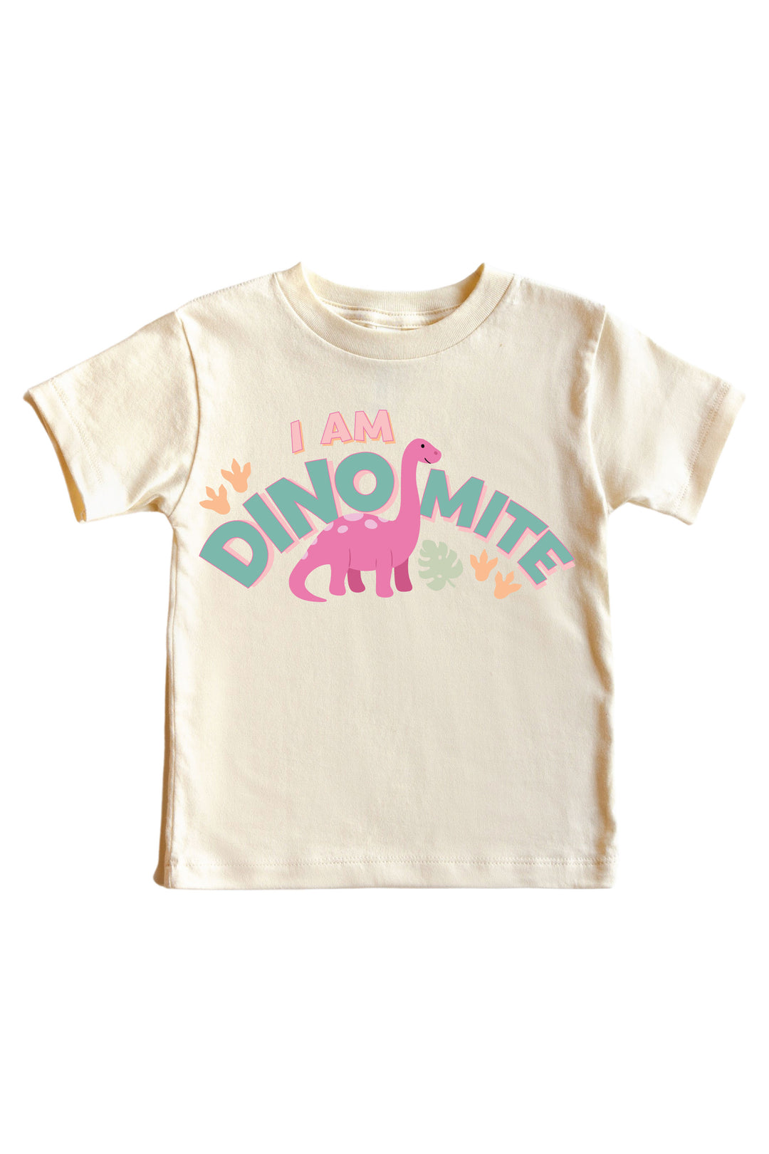 Natural cream kids tee with I AM DINOMITE text in teal and pink lettering featuring a pink brontosaurus dinosaur graphic with colorful leaf accents