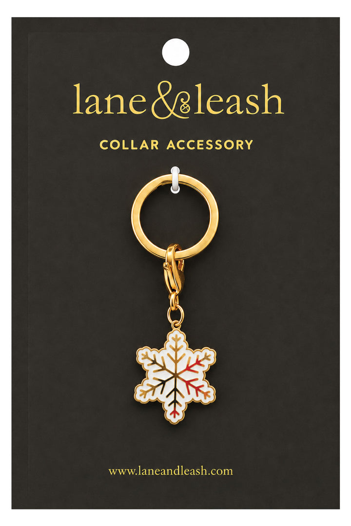 Lane & Leash snowflake charm collar accessory on branded packaging card, gold ring with lobster clasp and white enamel snowflake charm with gold and red accents
