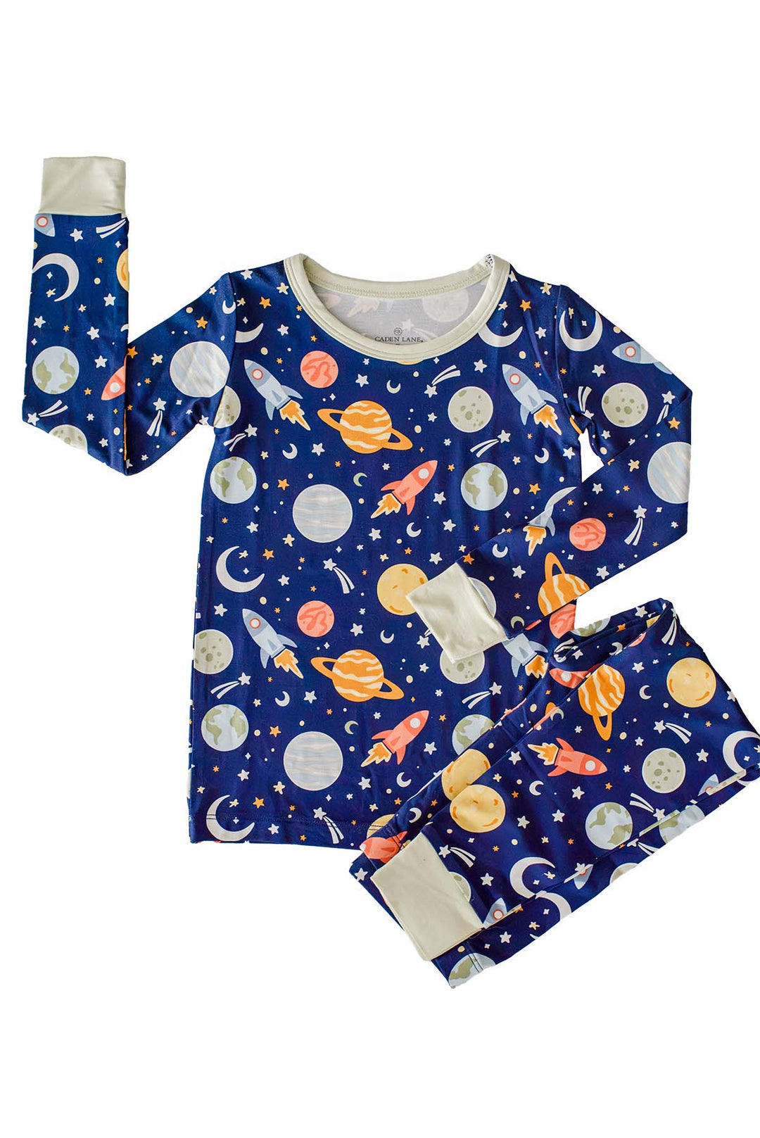 Flat lay of a Caden Lane navy bamboo pajama set, one sleeve raised playfully beside folded pants, in a Stellar Snuggles print featuring Earth, moons, and rockets.