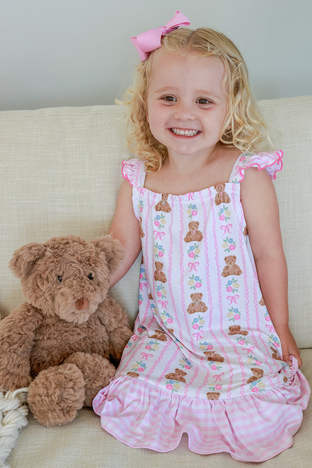 Young girl sitting with teddy bear smiling wearing Full Length Ruffle Nightgown in Beary Lovely print, front view showing pink ruffle hem