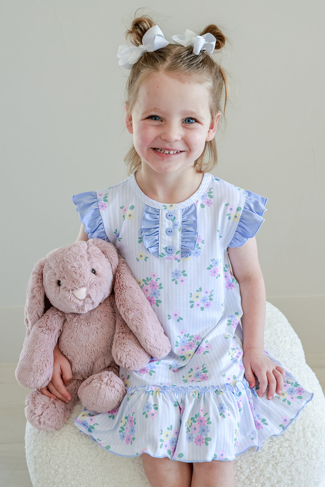 Young girl holding pink stuffed bunny wearing Flutter Sleeve Nightgown in Heirloom Posies blue floral print with ruffled collar and ruffle hem
