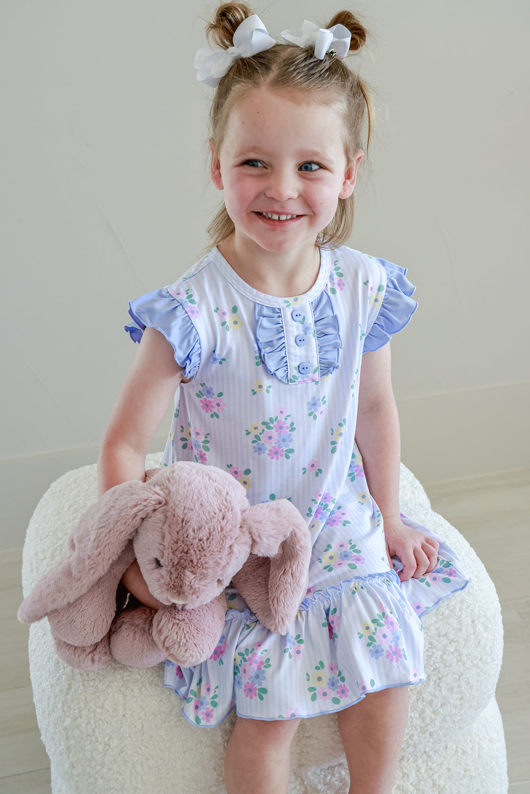 Young girl sitting holding pink stuffed bunny wearing Flutter Sleeve Nightgown in Heirloom Posies, smiling front view