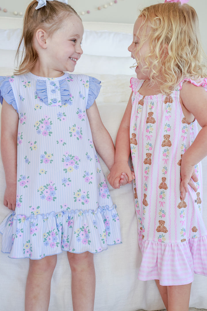 Two girls holding hands wearing summer nightgowns: Flutter Sleeve Nightgown in Heirloom Posies blue floral (left) and Beary Lovely teddy bear print (right)