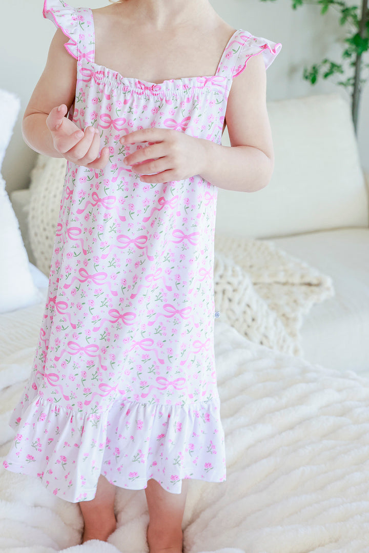 Young girl wearing Full Length Ruffle Nightgown in Dreamy Bows print, smiling pose showing flutter sleeves and ruffle hem