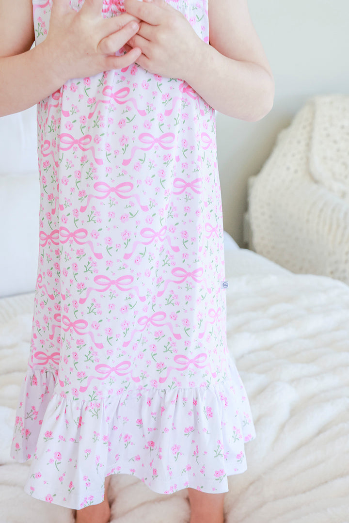 Close-up detail of Full Length Ruffle Nightgown in Dreamy Bows print showing pink bow and floral pattern fabric and ruffle hem