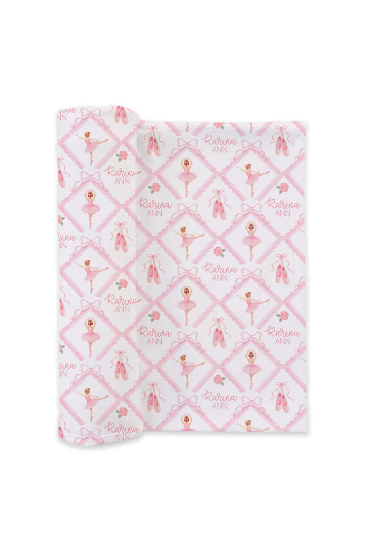 Folded Caden Lane ballerina and roses pink print personalized swaddle embroidered with the name 'Karina Ann,' flat lay on a white background