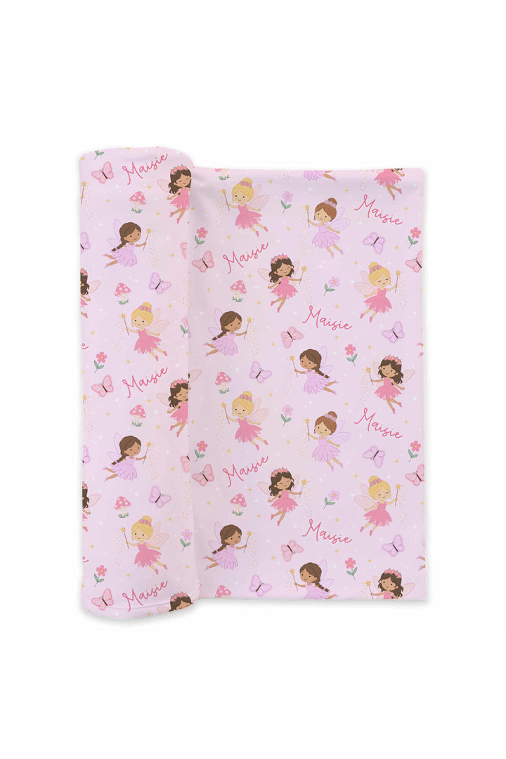 Fairy Wishes personalized swaddle blanket partially rolled, showing pink fairies, butterflies and a repeating custom name print
