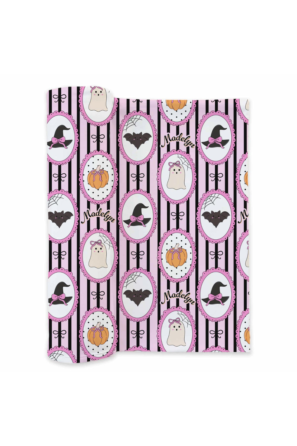 Rolled personalized Halloween swaddle blanket fabric with witch hat, bat, ghost, and pumpkin pattern and the name 'Madelyn' in cursive.