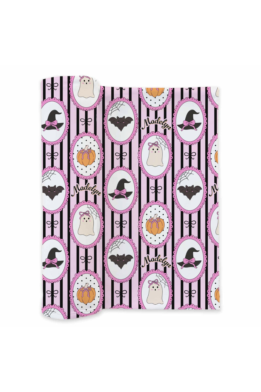 Rolled personalized Halloween swaddle blanket fabric with witch hat, bat, ghost, and pumpkin pattern and the name 'Madelyn' in cursive.