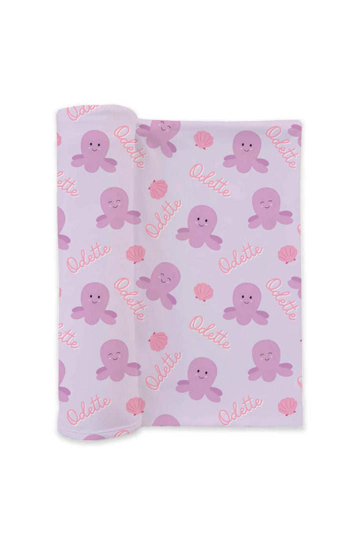 personalized sea snuggles swaddle blanket in lavender — rolled product view showing purple octopus, pink seashell print, and custom name