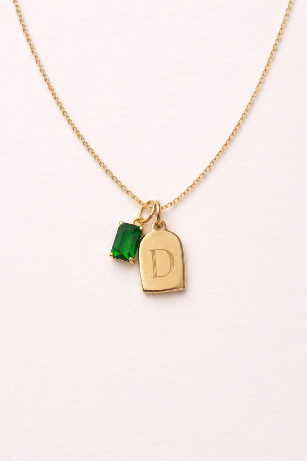 Caden Lane gold necklace with engraved initial "D" tag charm and green birthstone charm