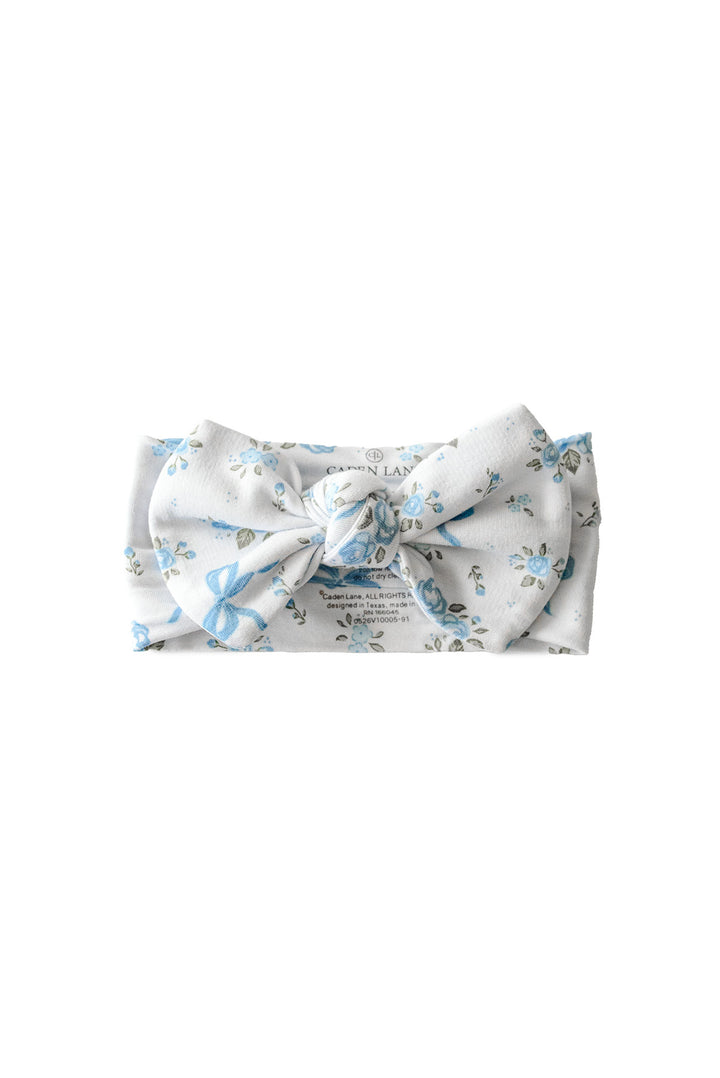 Tied In Blooms knit large bow headwrap in blue floral and bow print, shown as a knotted top-knot headband