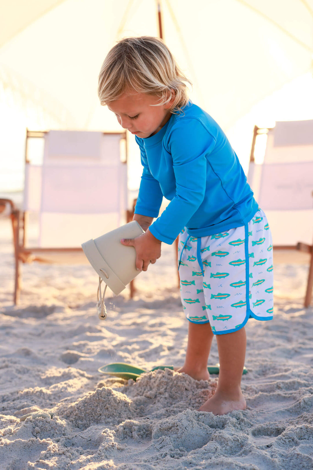 boy playing on the beach in blue long sleeve rash guard shirt with trout swim trunks 