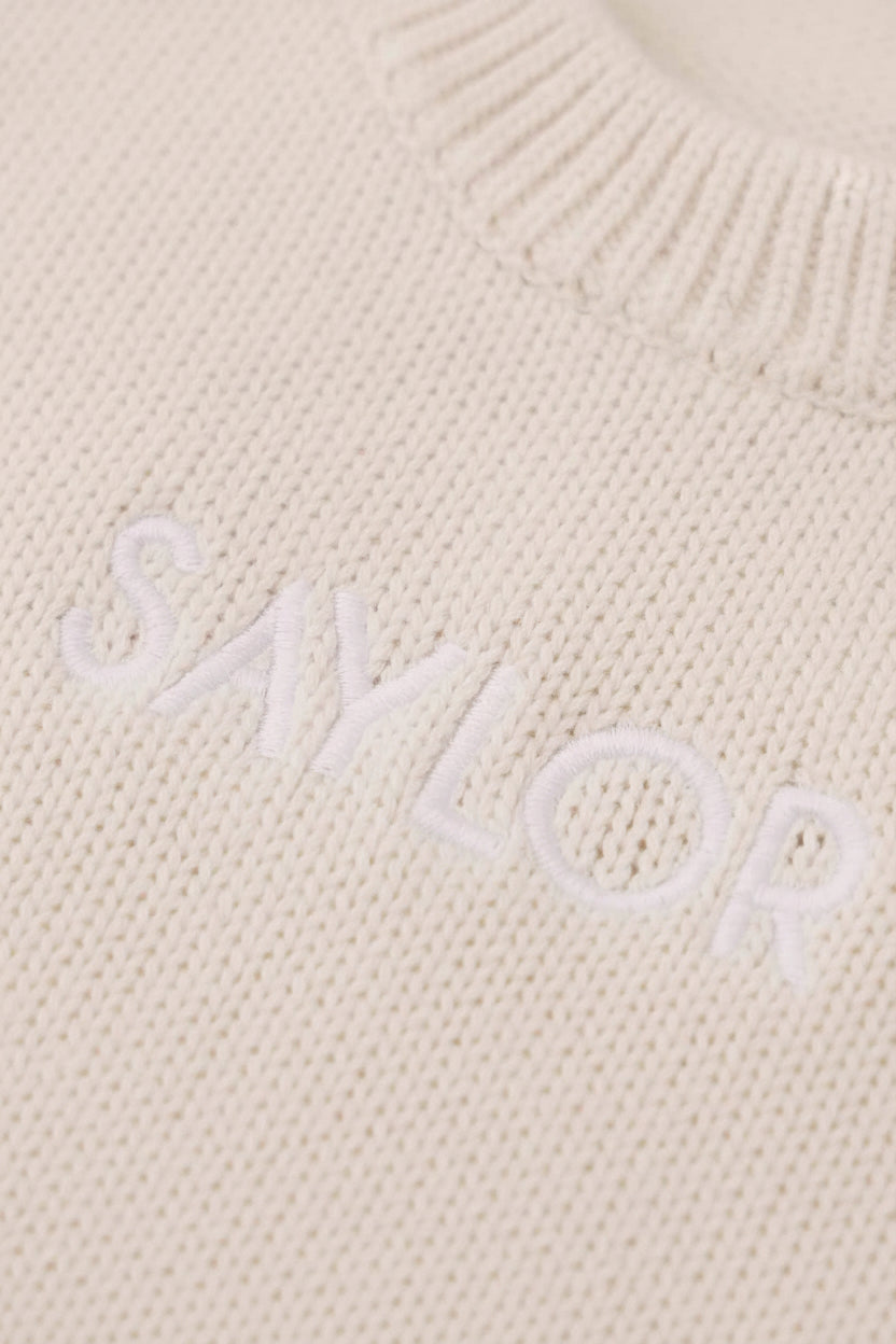 ash knit embroidered long sleeve sweater romper for babies with white thread in block font 
