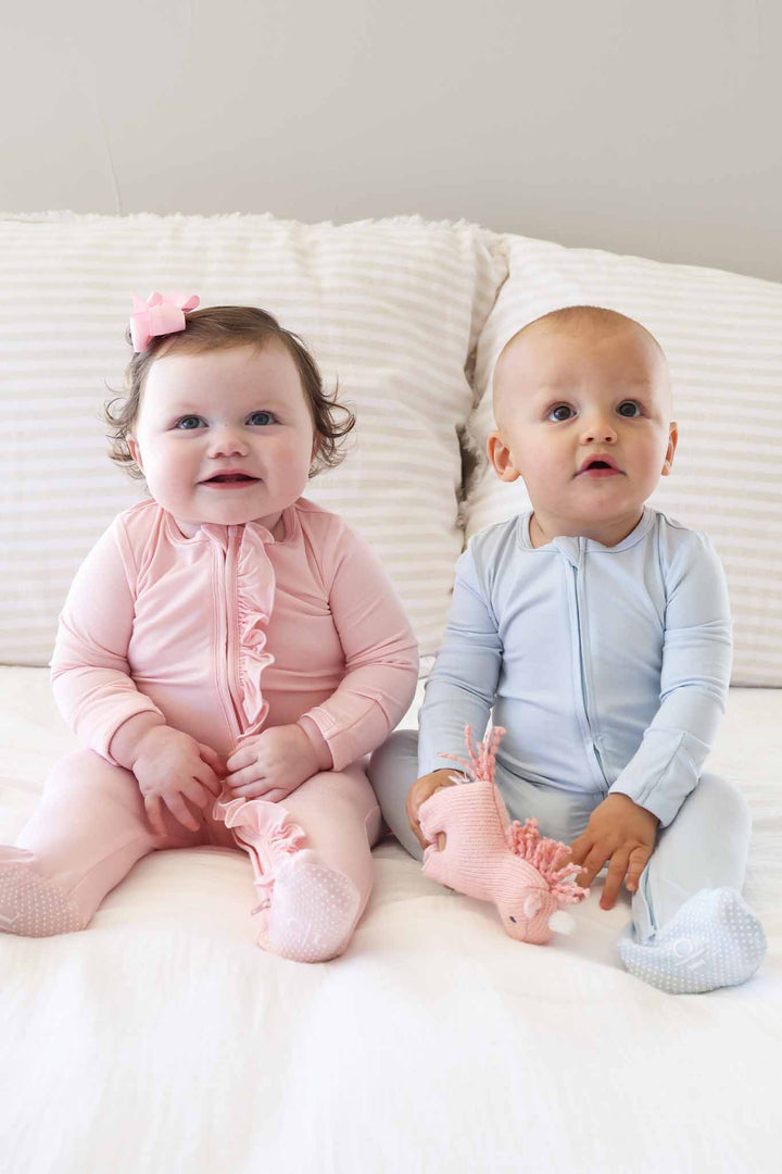 two sitting babies in pastel blue and pink footies