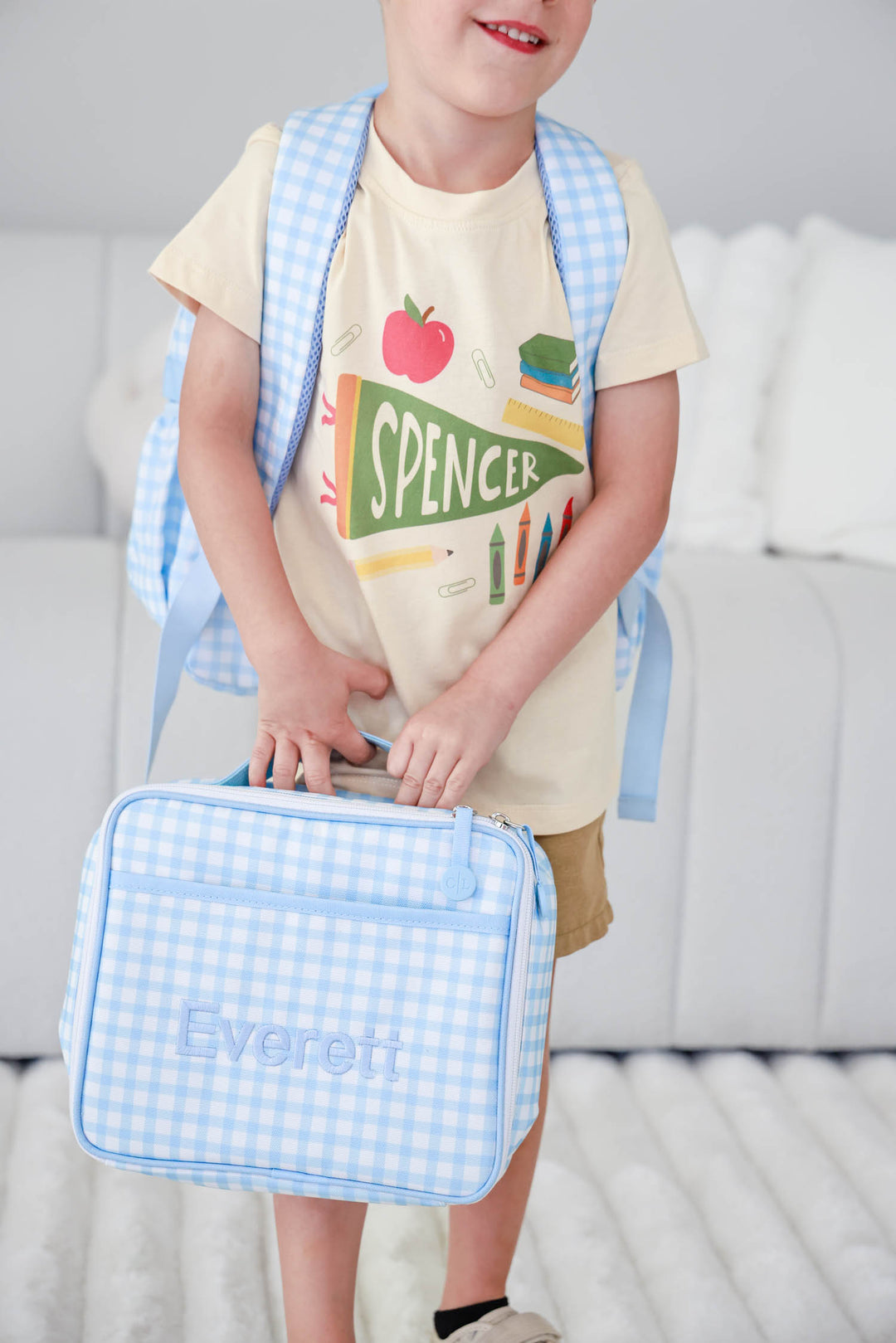 boy holding back to school blue gingham embroidered lunchbox and backpack with personalized t-shirt