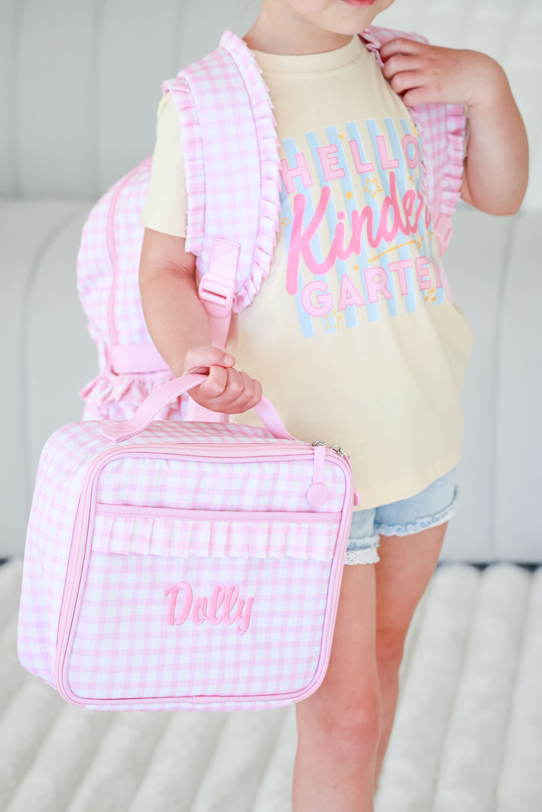 closeup of pink gingham embroidered lunchbox and hello kindergarten graphic tee