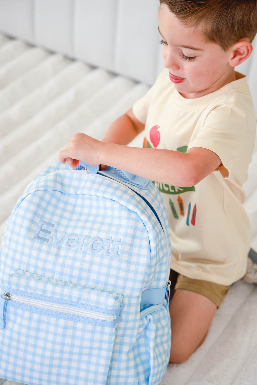 boy zipping blue gingham embroidered backpack