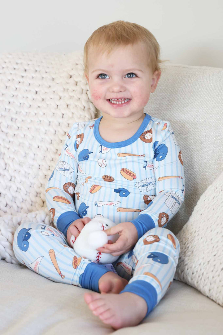 boy wearing ballpark bros  pajama set holding stuffed baseball 