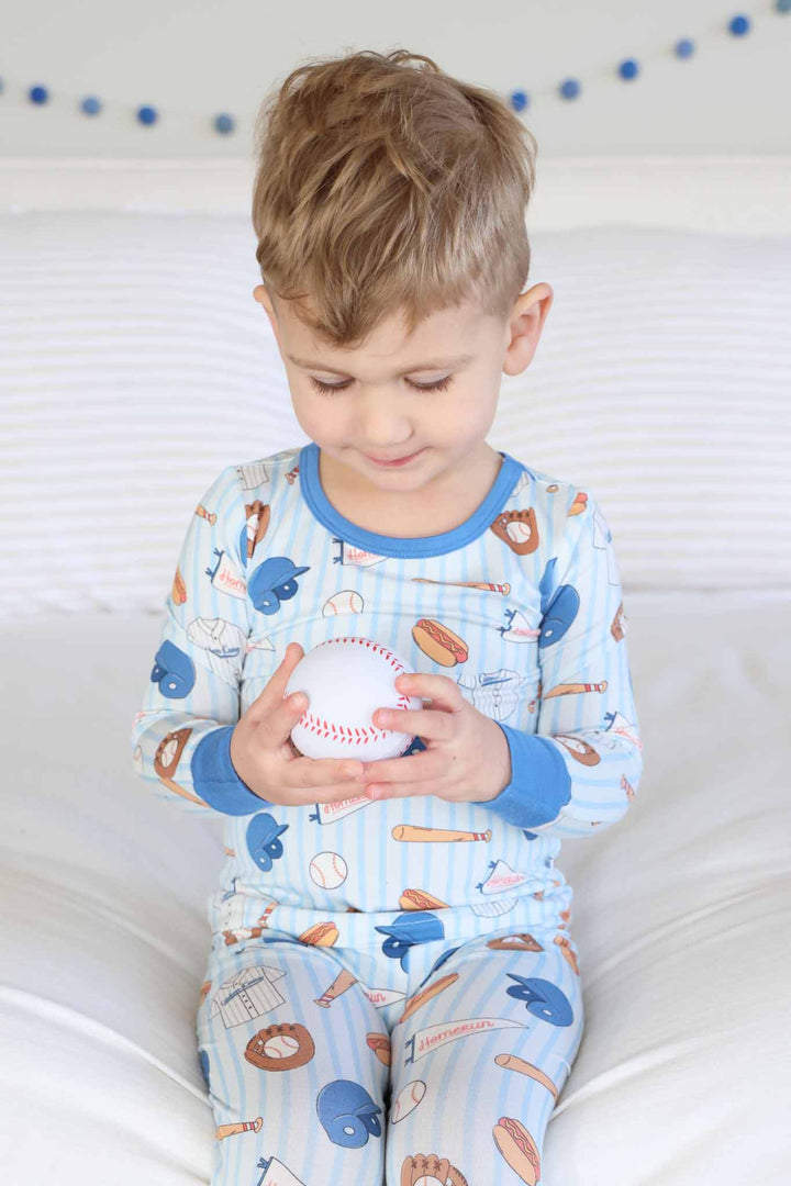 boy looking down at baseball in blue striped baseball themed pajama set 