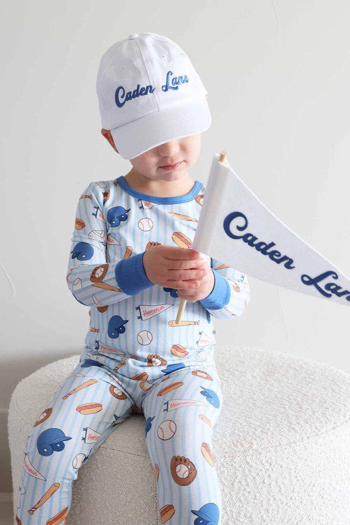 boy wearing baseball themed two piece pajama set with a caden lane baseball cap and banner