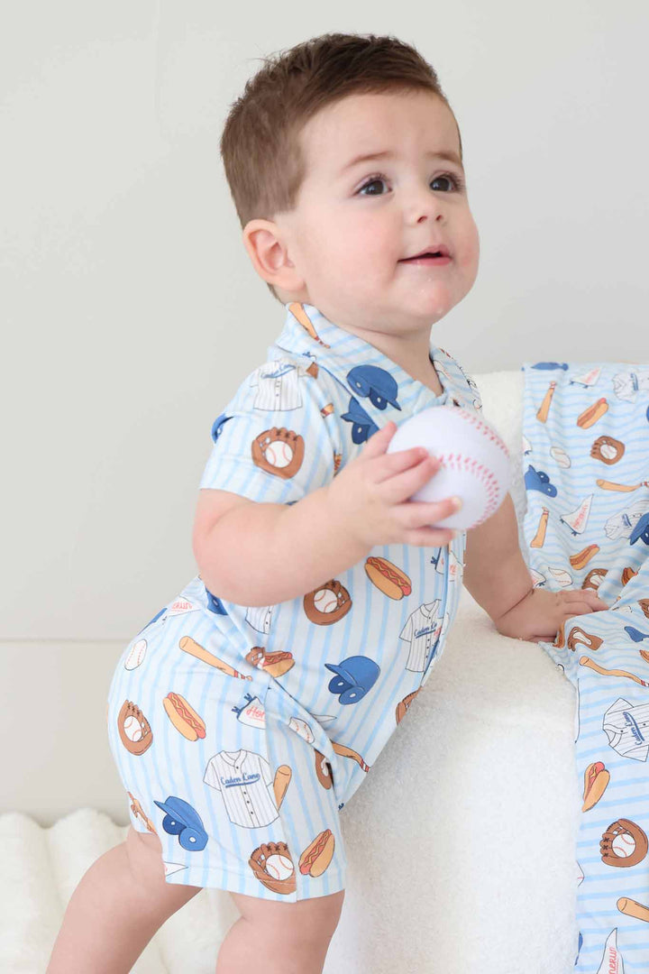 baby boy wearing stripes baseball collared romper holding a stuffed baseball 