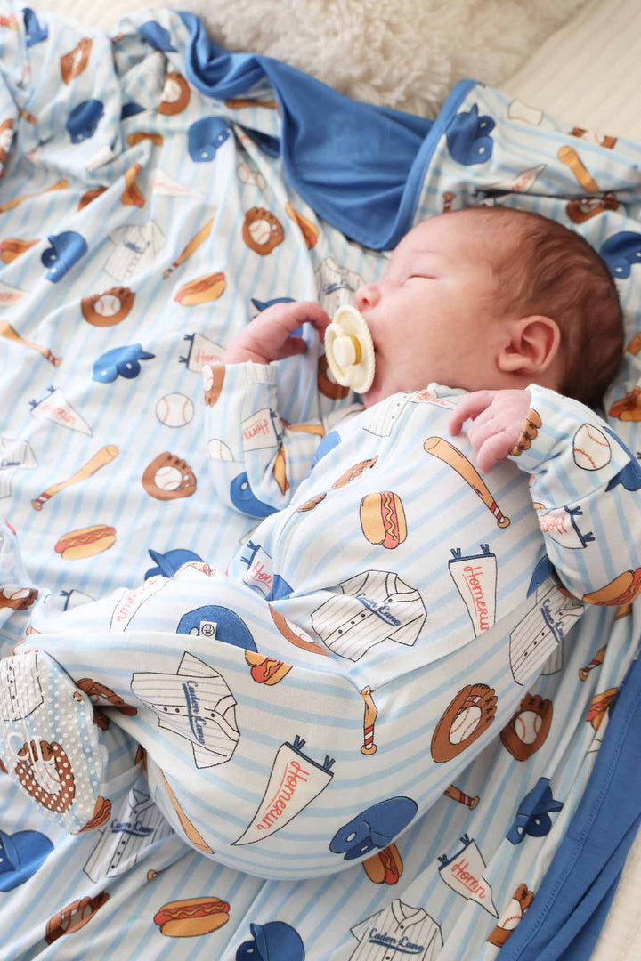 baby boy laying on side with pacifier in baseball bros zipper footie 