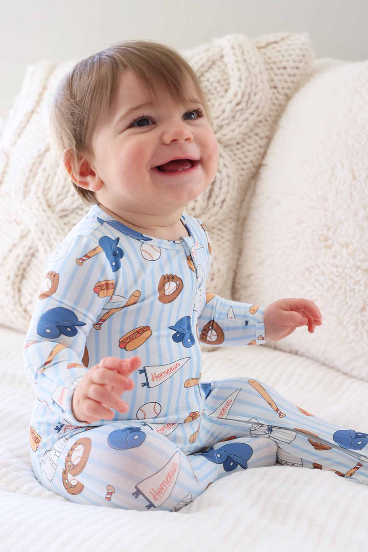 side view of ballpark bros striped zipper footie pajama on sitting baby boy 