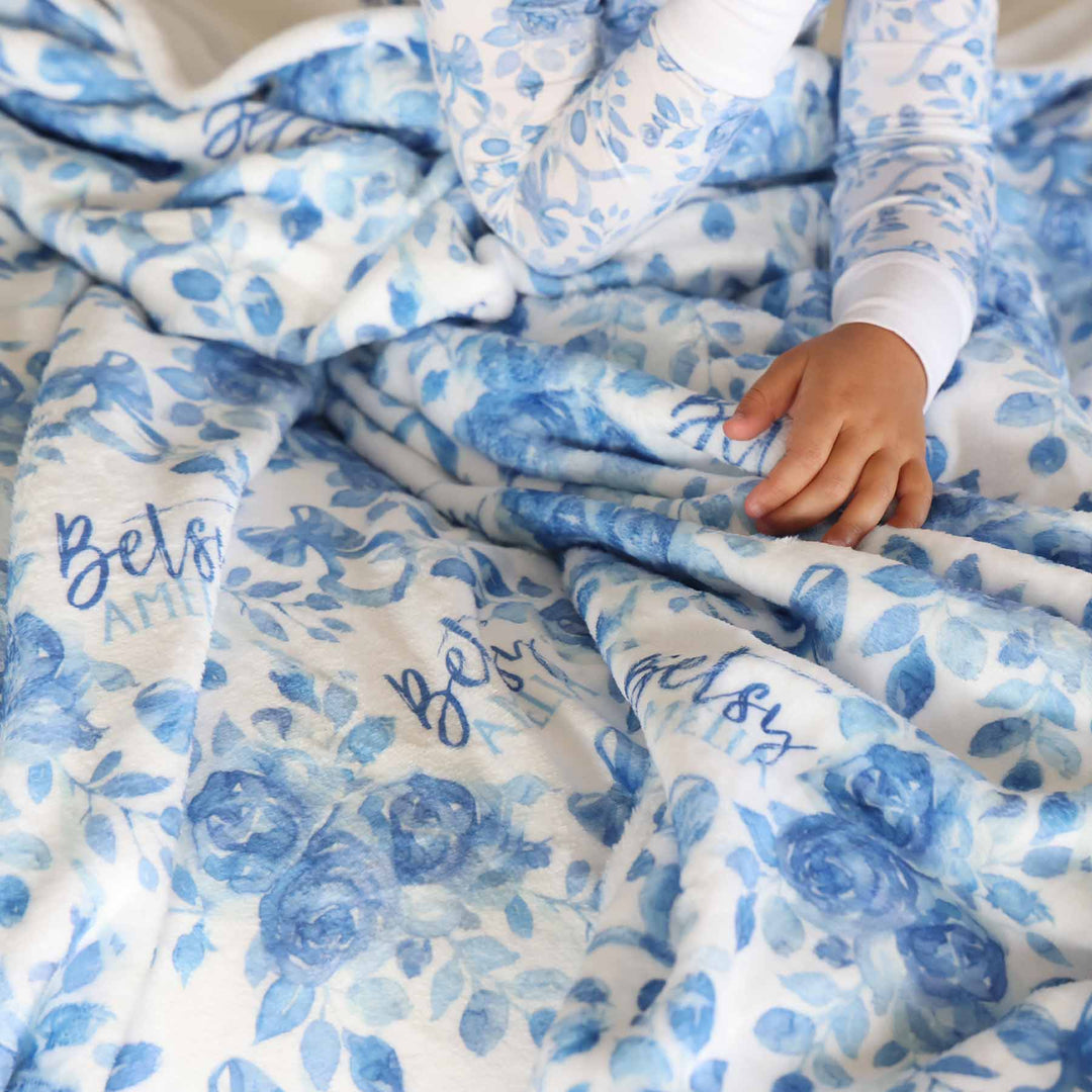 white blanket with blue flowers and bows and personalized with name 