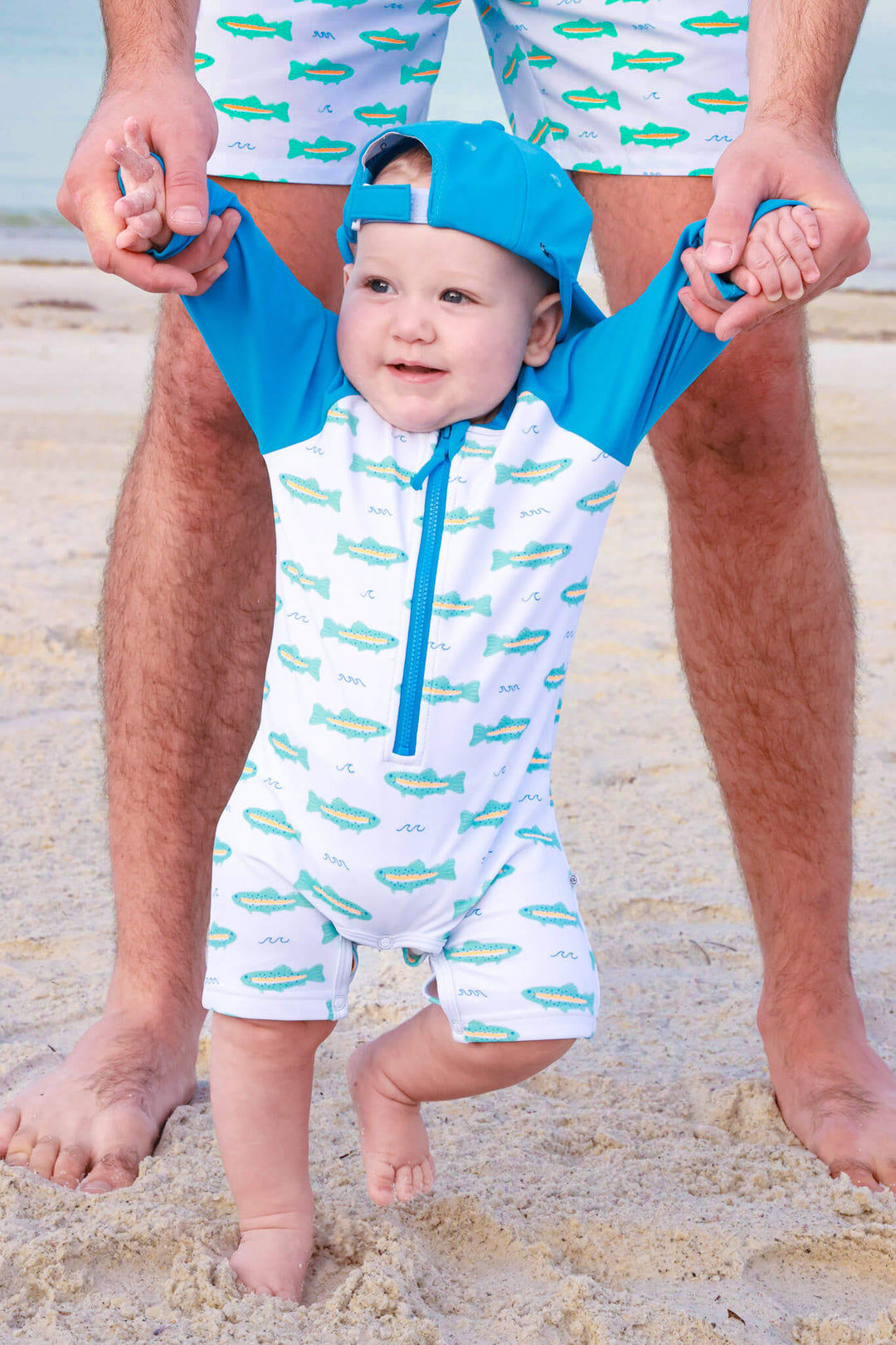 baby walking on beach in tiny trout long sleeve swim romper