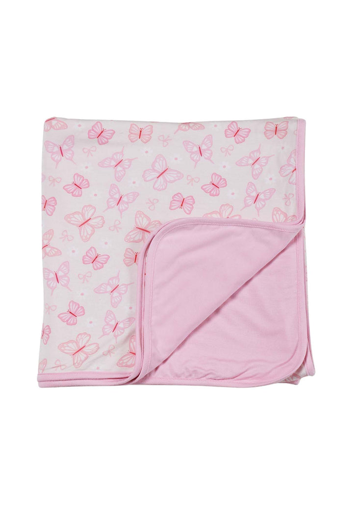 Double Sided Bamboo Blanket in Blooming Butterflies print - blanket folded with corner turned back to show both sides: white with pink butterfly print and solid pink reverse