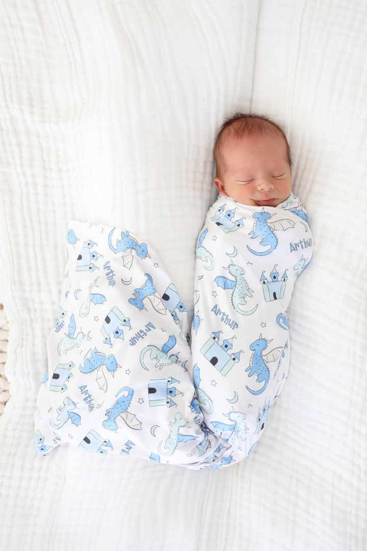 baby boy wrapped in personalized swaddle blanket with pastel dragons and castles
