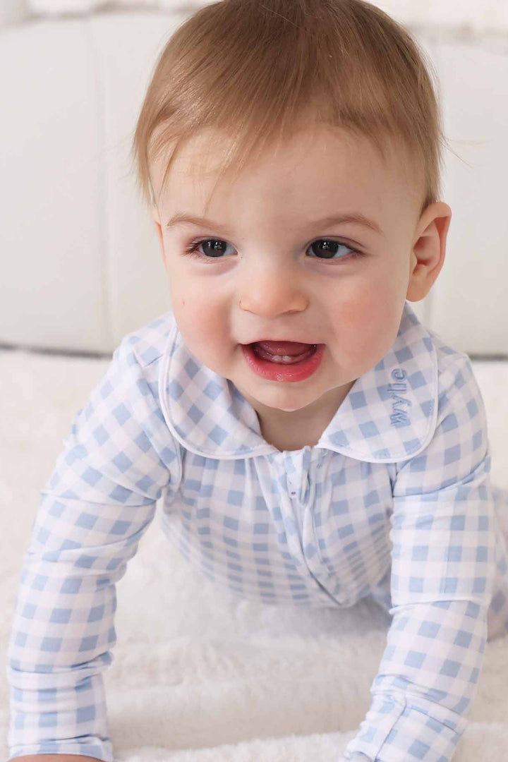 baby wearing light blue gingham footie onesie with personalized embroidery on collar