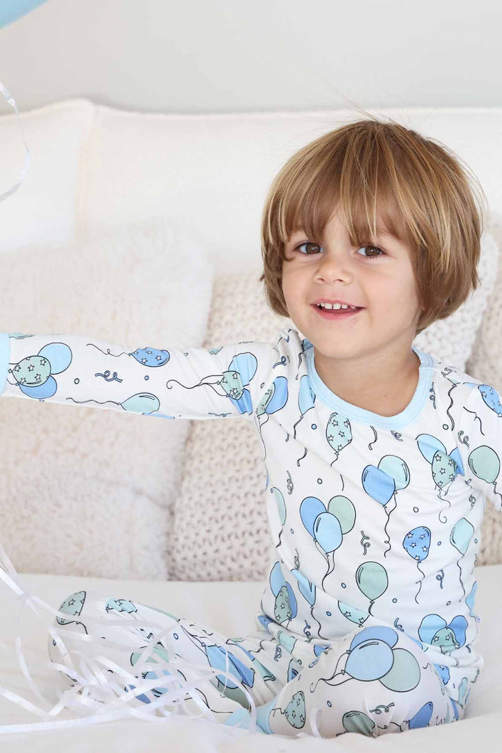 boy holding balloons wearing a blue balloon pajama set 