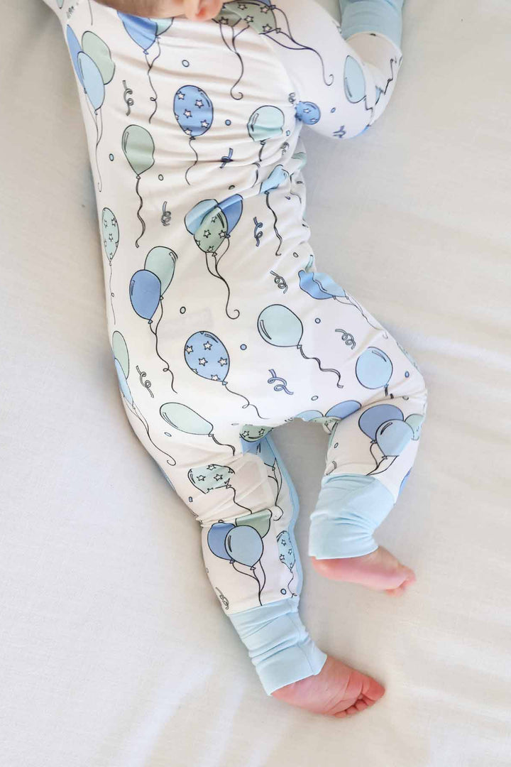 baby boy laying on stomach wearing balloon pajama romper 