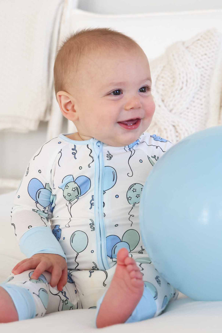 boy wearing balloon convertible zip romper holding a balloon