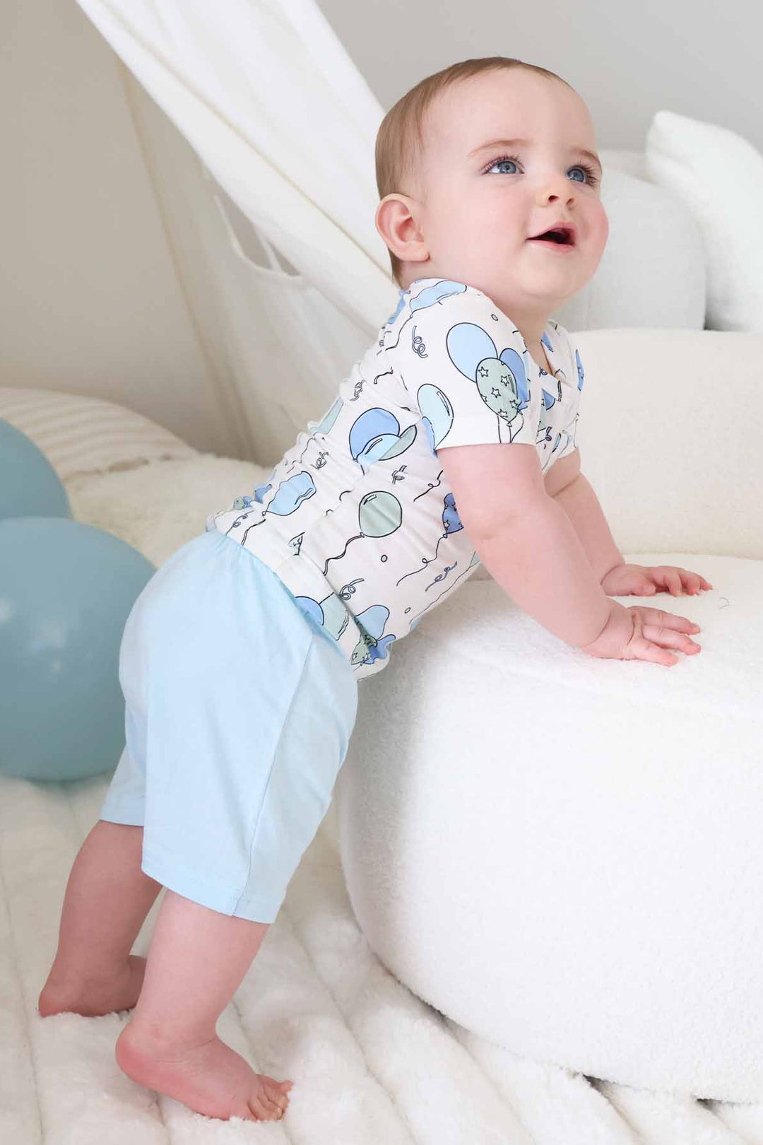 bow leaning on ottoman wearing a short sleeve balloon shirt with matching light blue shorts 