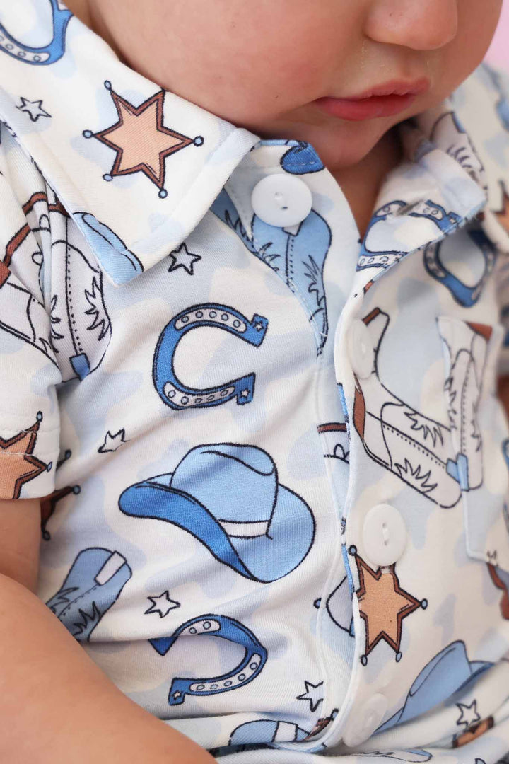 closeup of blue rodeo dreams print in collared button romper style 