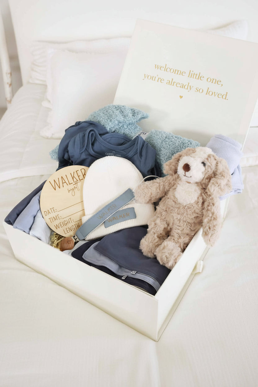 baby shower gift box bundle with blue pajamas, blankets, burps, and stuffed toy animal for boy