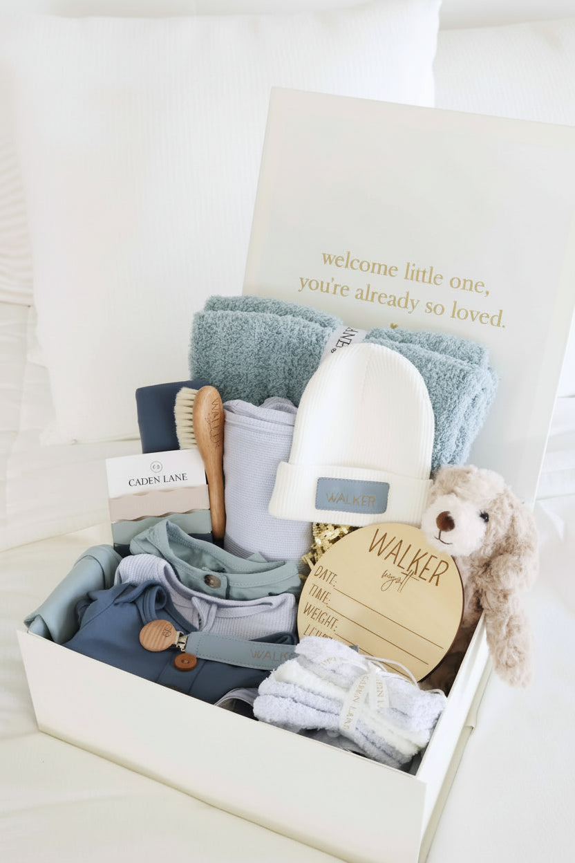 deluxe baby shower gift box bundle for boys with blue 2pc waffle, zipper footie, knot gown, wood  stats, swaddles, bottle labels, burps, socks, paci clip, beanie, lovey, blanket, hooded towel, hair brush, dog stuffed animal