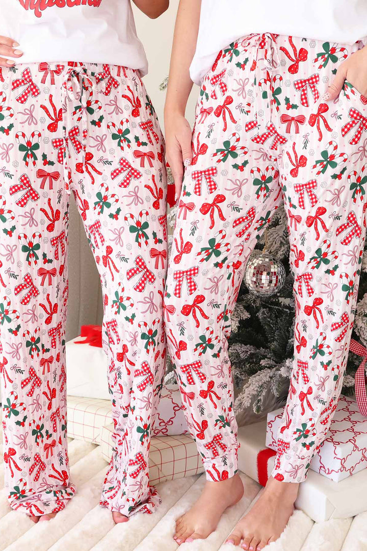 Pajama pants with white and light pink stripes background plus various red bows on top. Unisex Lounge and Jogger styles.