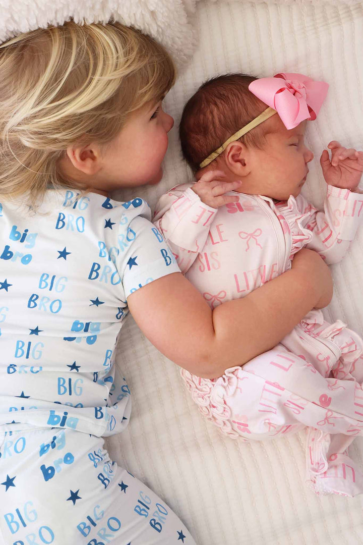 big brother with his arm around little sister in matching sibling pajamas 